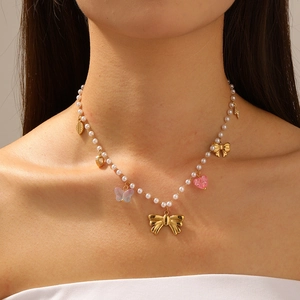 Beaded gold necklace with colorful acrylic butterflies and heart pendants on a model