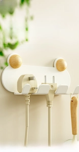 Wall-mounted white power plug holder with wooden knobs and multi-slot cable organizer