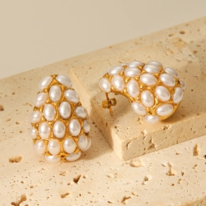Water-drop stainless steel stud earrings with pearls on natural beige stone background