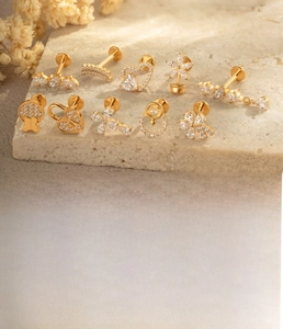 Macro shot of gold titanium heart and floral stud jewelry set with zircon on marble