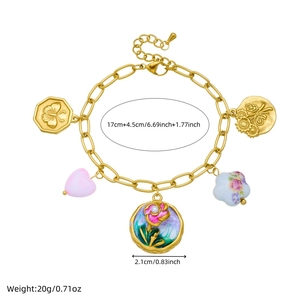 Golden bracelet with butterfly, pink heart, and enamel flower charms on white background