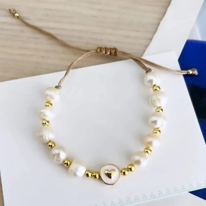 Detail of baroque pearl bracelet with gold heart charm and adjustable braided cord