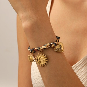 Leopard print silk ribbon bracelet with gold sun and heart pendants on a female wrist