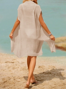 Detail of sheer beige beach cover-up showing light semi-transparent fabric in a sunlit view