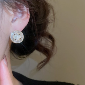 Close-up of gold plated round stud earring with clover zircon pattern on a model