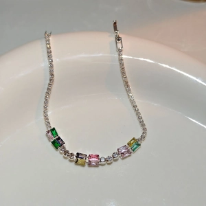 Detail of silver bracelet with colorful rectangular zircons on white ceramic base