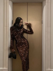 Détail de la robe marron à paillettes montrant les poignets luxueux en plumes d'autruche