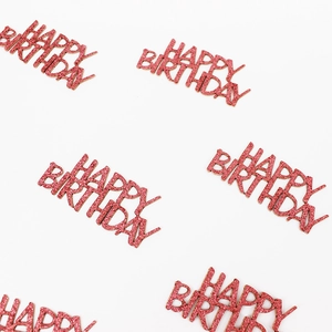 Close-up of pink glittery HAPPY BIRTHDAY confetti decorations on white background