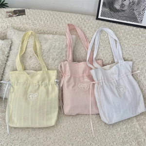 Detailed shot of textured corduroy tote bags with lace heart and bow drawstrings