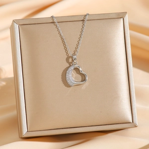 Collana con ciondolo a cuore minimalista con zirconi luccicanti su sfondo di seta champagne