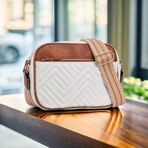 Detailed macro view of quilted V-pattern stitching on brown and white crossbody bag