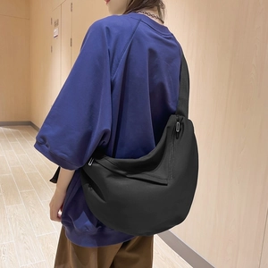 Black crescent messenger bag shown on model's back for size and capacity visual