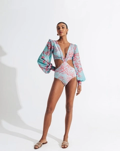 Close-up of long sleeve cutout swimsuit featuring blue fabric with pink coral patterns