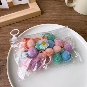 Detail of colorful plush pom-pom hair ties set in a transparent zipper jewelry bag