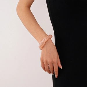Close-up of pink marbled acrylic cuff bracelet worn on wrist with black dress