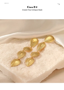Macro detail of golden teardrop earrings with beaded texture on white crystal stone