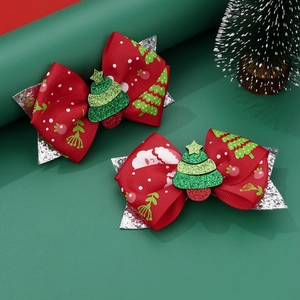 Close-up of red Christmas bow clips with sequined green tree decor and festive patterns