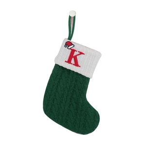 Macro shot of green cable knit Christmas stocking with red embroidered letter K detail