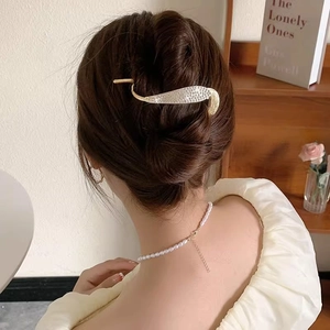 Elegant gold leaf-shaped rhinestone hair clip worn on back of head for a chic look