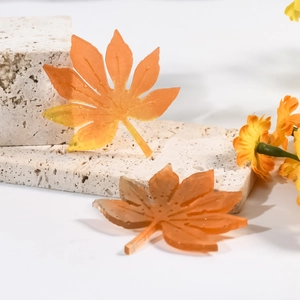 Détail de pendentif en feuille d'érable en résine avec dégradé orange et gouttes de rosée
