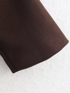 Detailed view of high-quality sewing on dark brown wool coat edge with contrast background