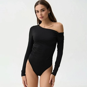Détail d'un body noir asymétrique à manches longues avec fronces sur fond blanc pur