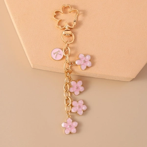 Detail view of pink cherry blossom charms and letter K pendant on a gold keychain