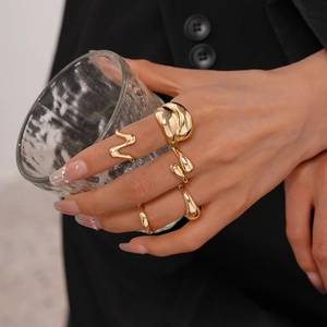 Nahaufnahme goldener geometrischer Ringe an einer Hand mit edlem schwarzem Anzug