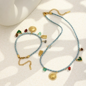 Détail du collier et bracelet bohème avec breloques soleil et pierres sur cordons tissés