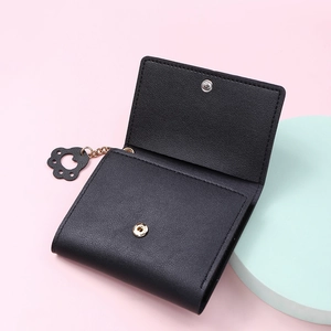 Close-up of black bifold wallet with lychee texture, gold snap, and cute cat paw charm