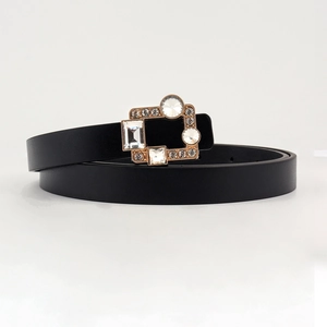 Close-up of gold hollow square buckle with crystals on a black PU leather belt