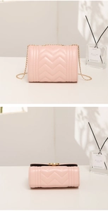 Detail view of pink quilted crossbody bag with gold chain and circular metal lock