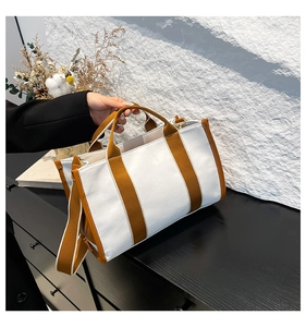 Detail of canvas tote bag with brown fabric handles and adjustable shoulder strap