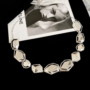 Collier en métal argenté poli à facettes géométriques sur un fond noir élégant
