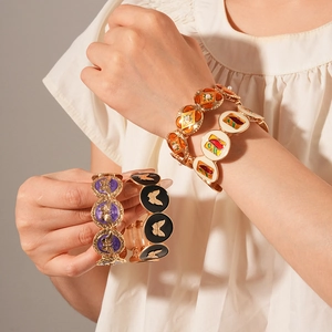 Detail of vintage enamel bangles with butterfly patterns and pearl accents on wrist