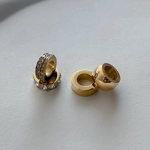 Vue macro de breloques en acier doré avec pavé de cristaux et finitions polies