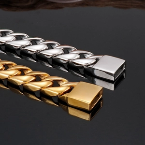Macro detail of polished gold and silver Cuban link bracelets with secure clasp