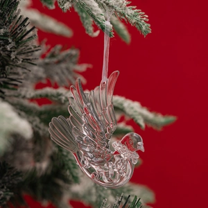 Macro detail of clear acrylic flying bird ornament with feather textures on Christmas tree