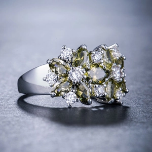Macro di un anello d'argento con pietre preziose marquise verdi in un grappolo floreale