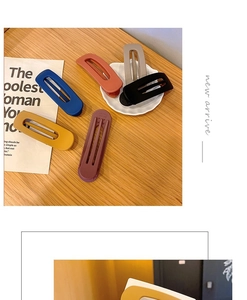 Detailed view of large matte hair clips in assorted colors on a wooden desktop