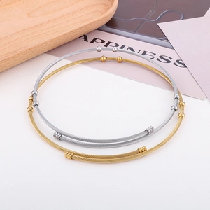 Detail of gold and silver twisted wire chokers with round beads on a wooden tray