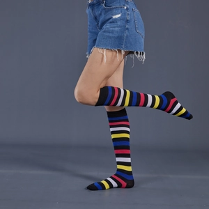 Detail shot of mid-calf socks with colorful rainbow stripes on a model wearing denim