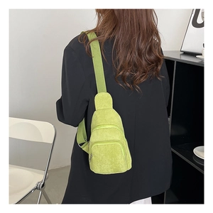 Hellgrüne Cord-Umhängetasche an einem Model in einem minimalistischen Innenraum