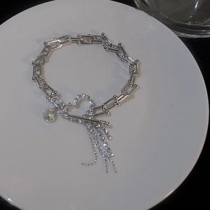 Close-up of heart-shaped T-bar clasp and rhinestone tassel detail on silver chain