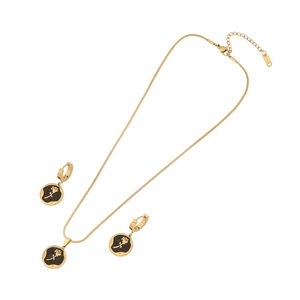 Vintage gold rose pendant necklace and earrings set with black resin inlay on white backdrop