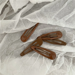 Detailed view of five brown water-drop BB hair clips on textured white paper backdrop