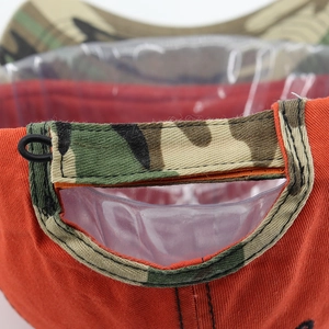 Close-up of orange baseball cap with camouflage back strap and detailed stitching