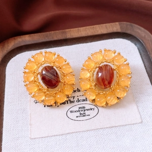 Macro shot of vintage gold earrings with amber beads and oval carnelian stone inlay