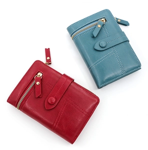 Detail view of red and teal PU leather tri-fold wallets with zip pockets and snap closure