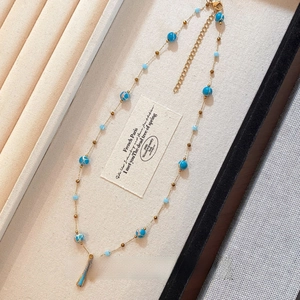 Detail of cross pendant necklace with blue stone beads in a velvet jewelry box